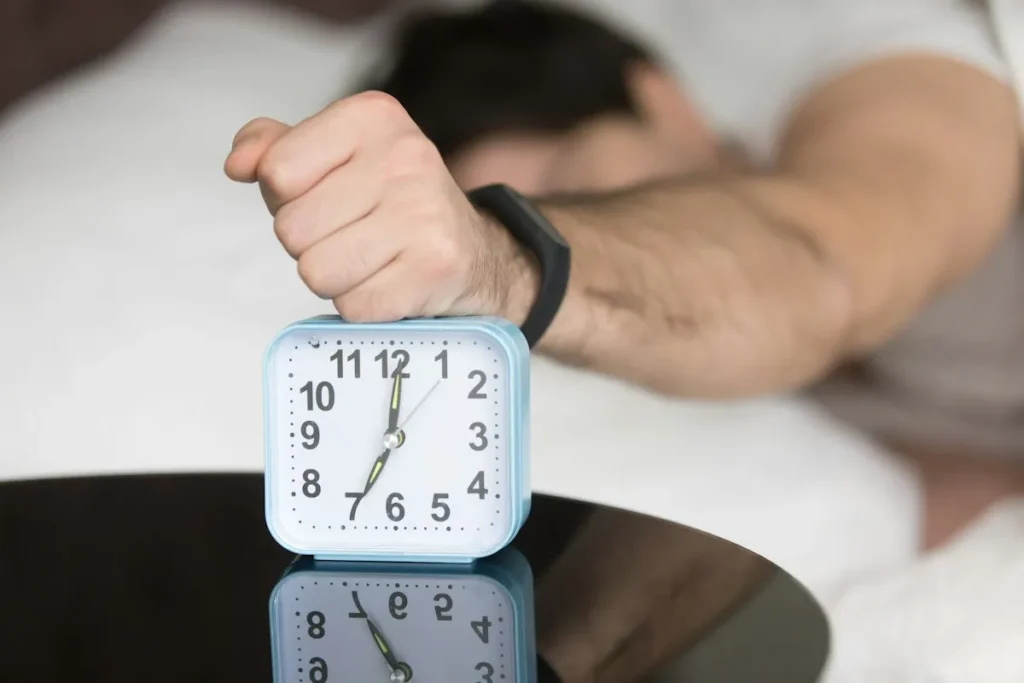 Persona apagando el despertador por la mañana en la cama
